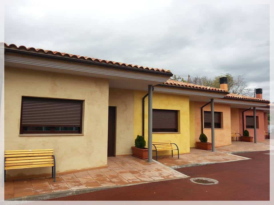 Viviendas en Benabarre con fachadas en tonos amarillos, naranjas y beige, con bancos y áreas exterio.