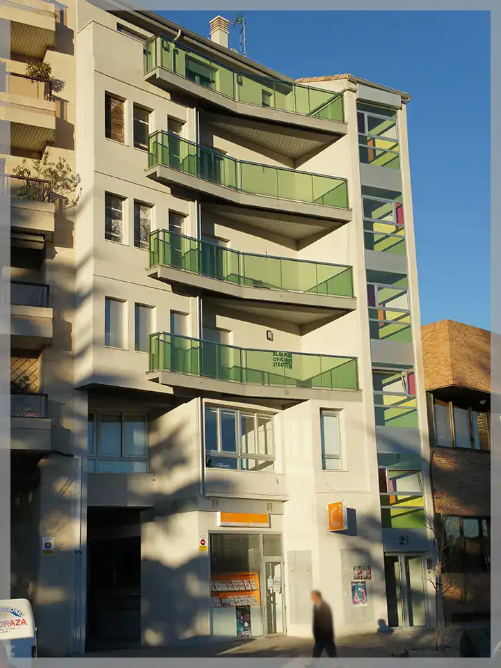 Edificio plurifamiliar moderno con balcones verdes y diseño innovador.
