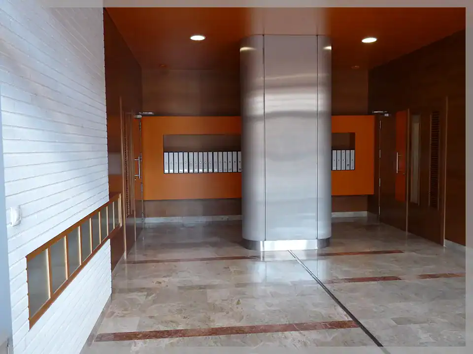 Puerta de entrada moderna en edificio plurifamiliar con diseño funcional y seguro.