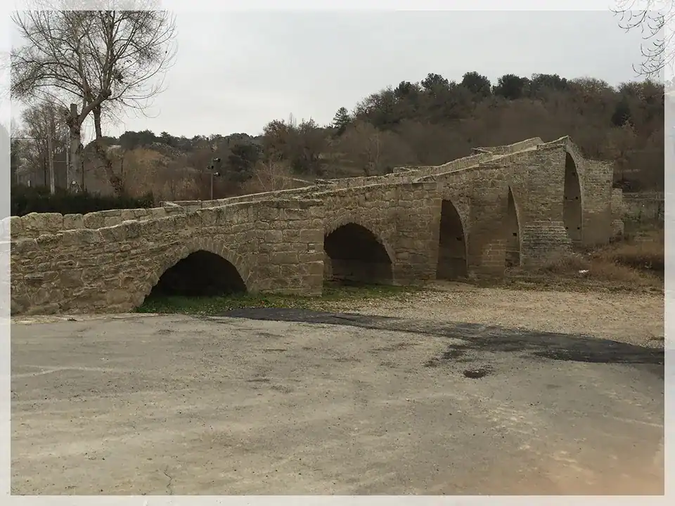 Puente de piedra restaurado en entorno rural, ejemplo de conservación arquitectónica.